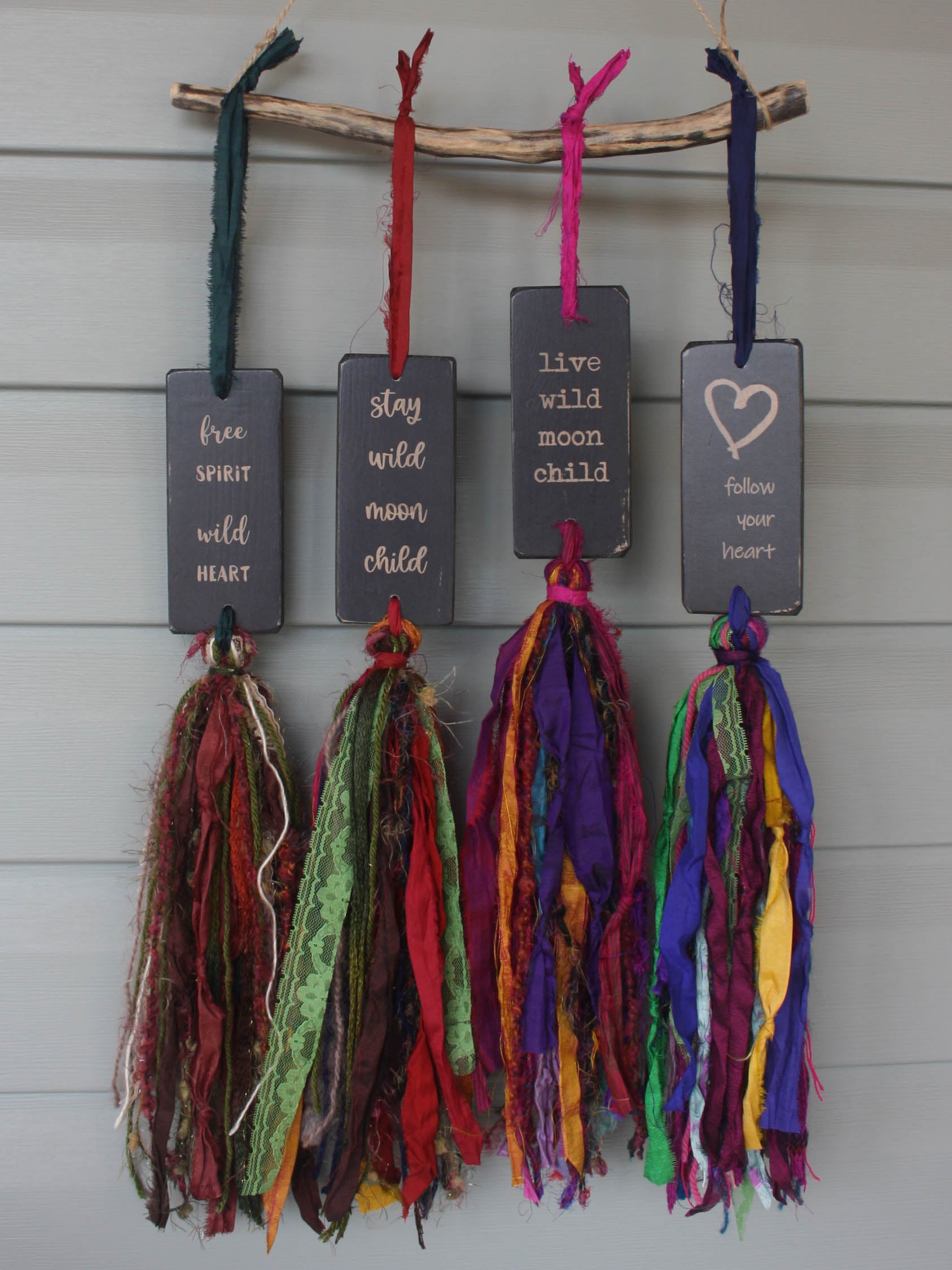 a series of rectangular pieces of wood in distressed black with the text  and a colourful multicoloured tassel.