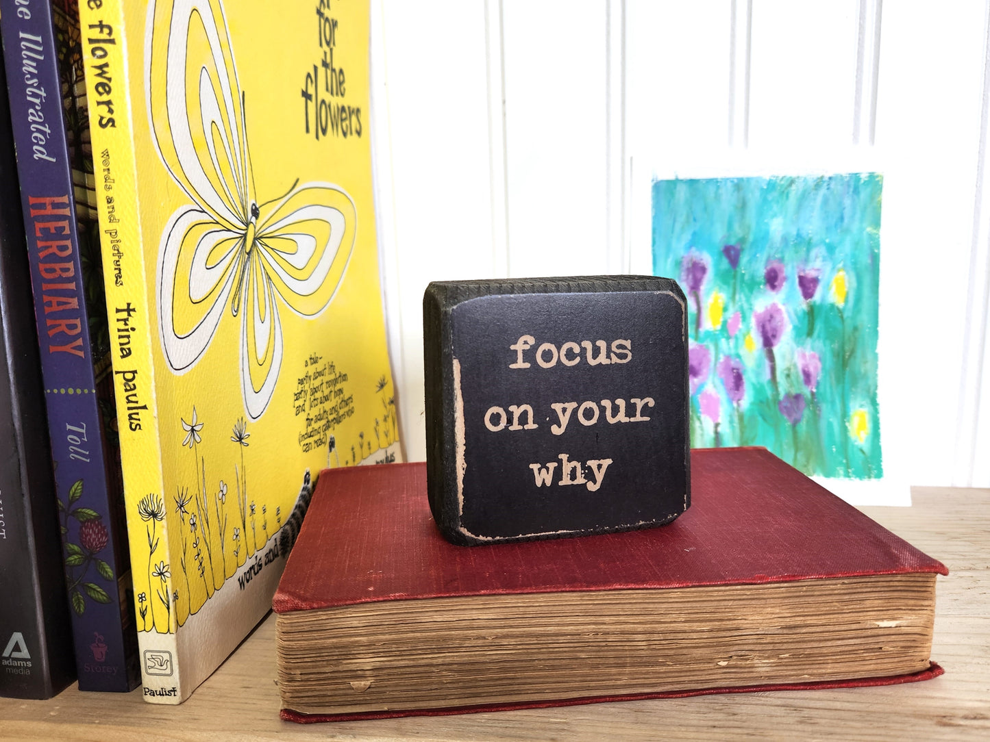 Book with a motivational quote on top of other books with colorful covers.