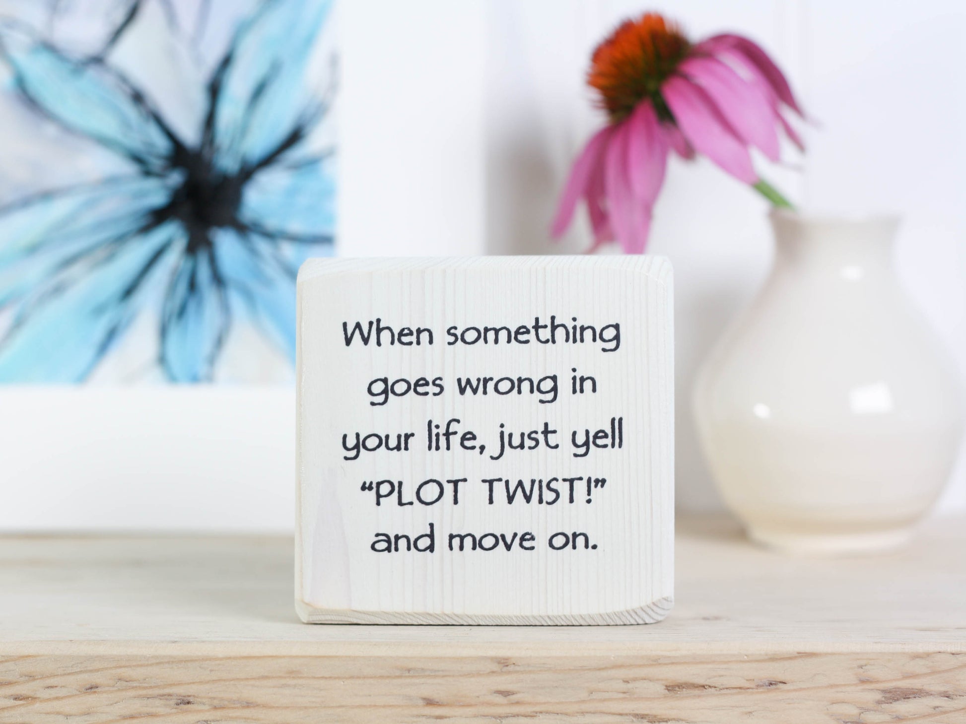 Small whitewashed wood sign with the saying "when something goes wrong in your life, just yell "PLOT TWIST" and move one.