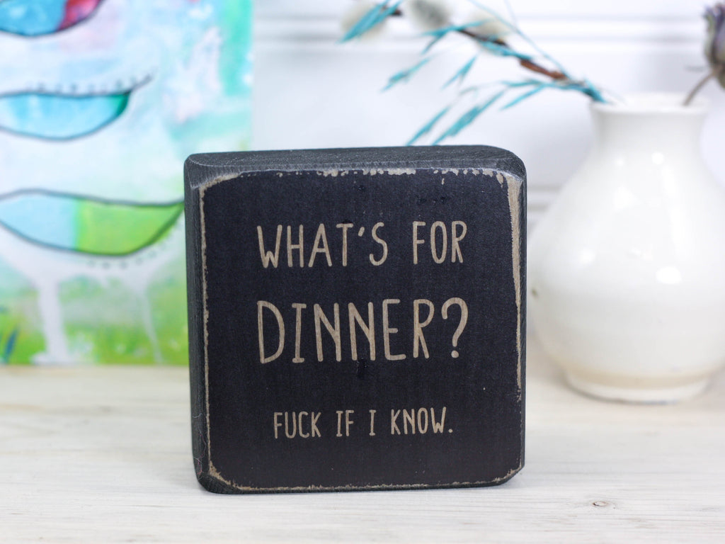 Small distressed black freestanding wood sign with the text "what's for dinner? Fuck if I know."