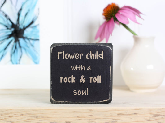 Small, freestanding, distressed black, solid wood sign with saying "Flower child with a rock & roll soul".