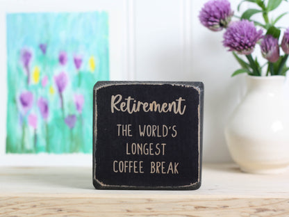 Small wood sign in distressed black with the text "Retirement: the world's longest coffee break