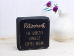 Small wood sign in distressed black with the text "Retirement: the world's longest coffee break