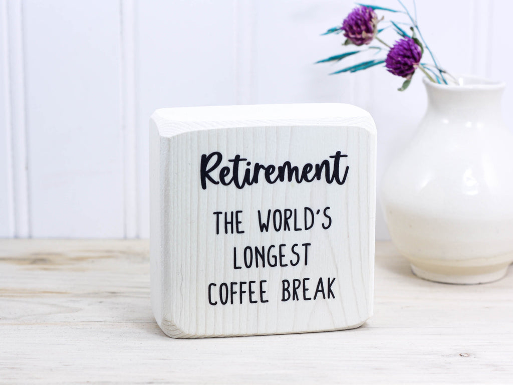 Small wood sign in whitewash with the text "Retirement: the world's longest coffee break"