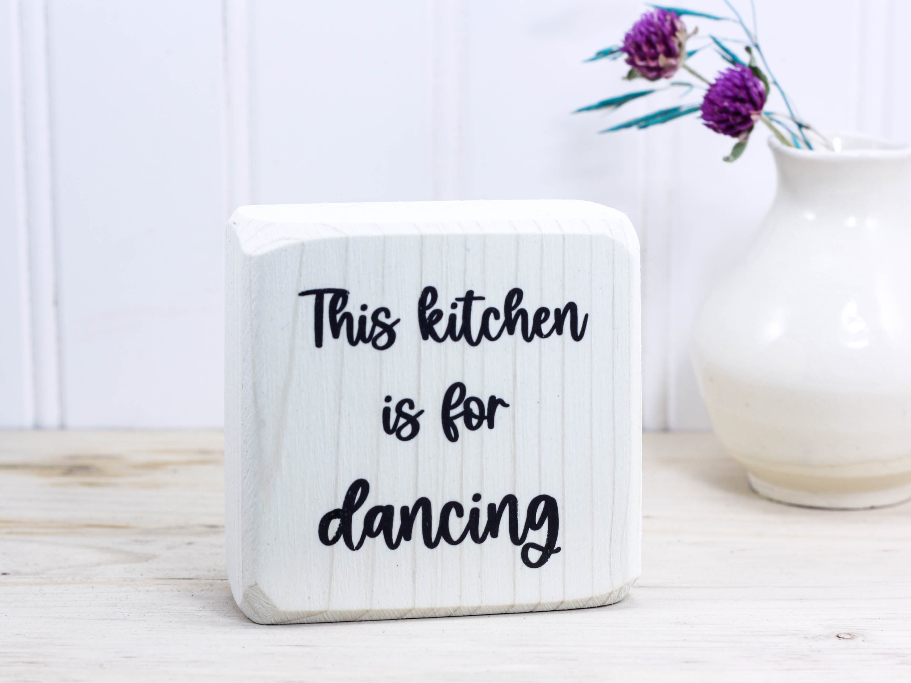 Small wooden decor in whitewash with the saying "This kitchen is for dancing".