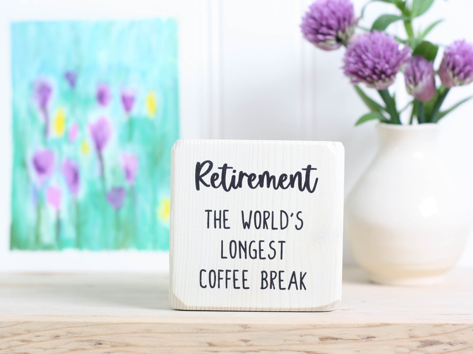 Small wood sign in whitewash with the text "Retirement: the world's longest coffee break"