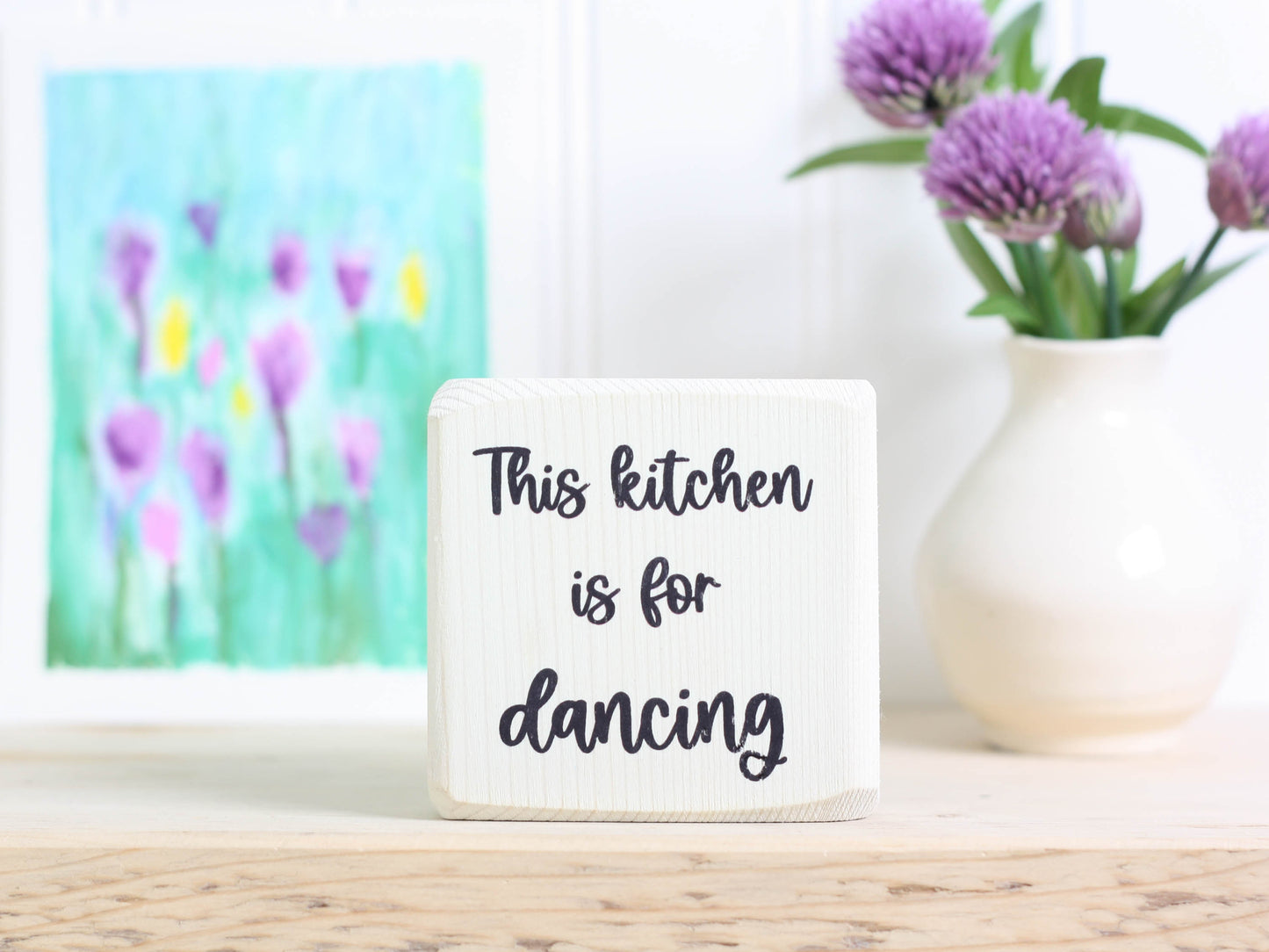 Small wooden decor in whitewash with the saying "This kitchen is for dancing".