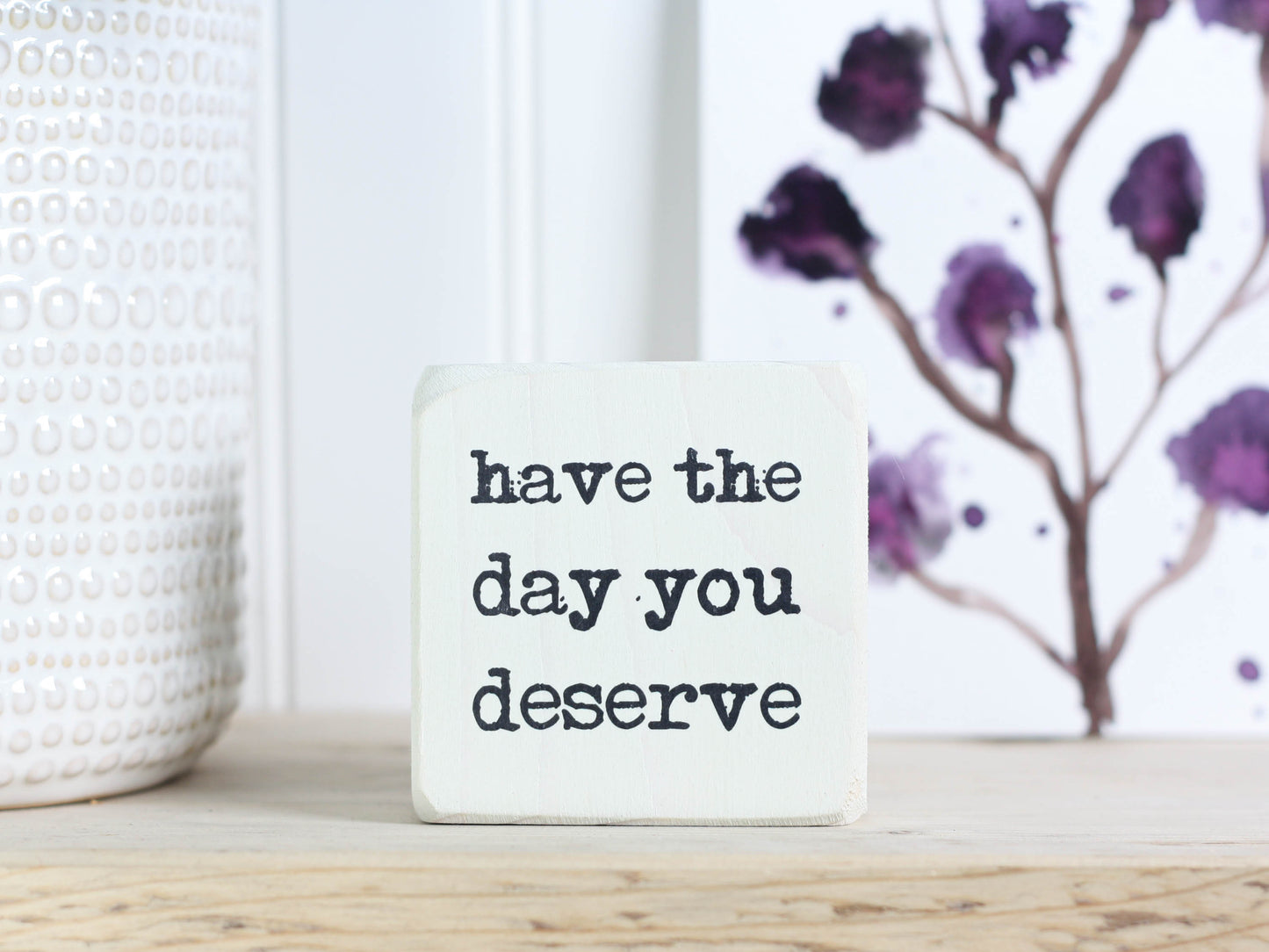 small wood sign in whitewash with the text "have the day you deserve"