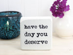 small wood sign in whitewash with the text "have the day you deserve"
