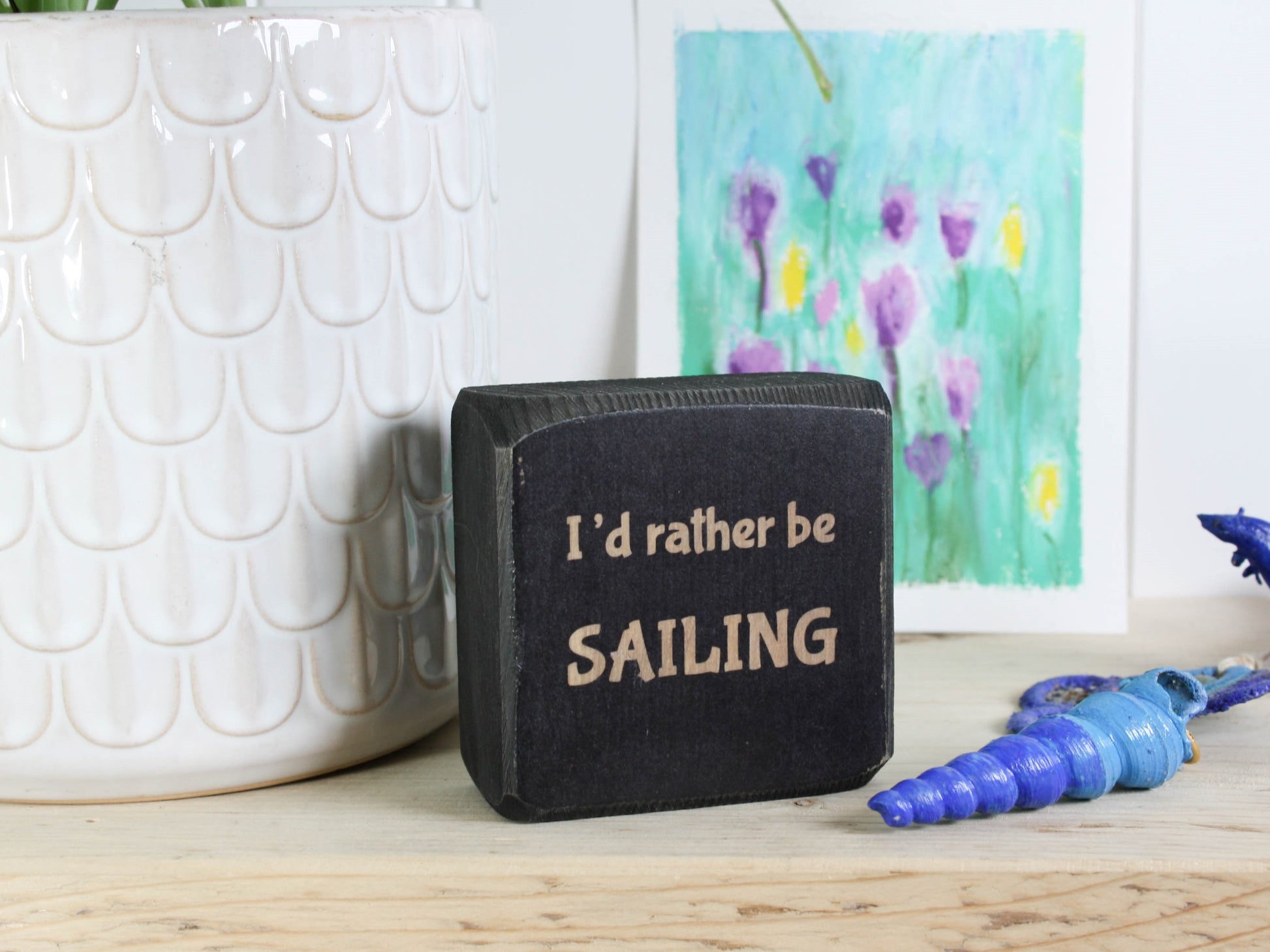 Small distressed black wood sign with the saying "I'd rather be sailing"