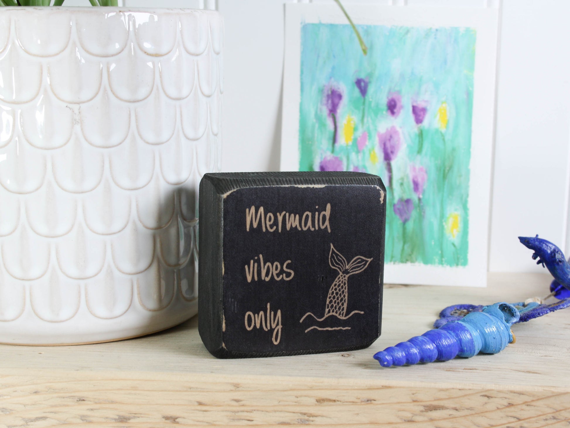 Small distressed black wood sign with the text "mermaid vibes only"