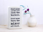 Small funny wood kitchen sign in whitewash with the saying "Good moms let their kids lick the beaters. Great moms turn the mixer off first."