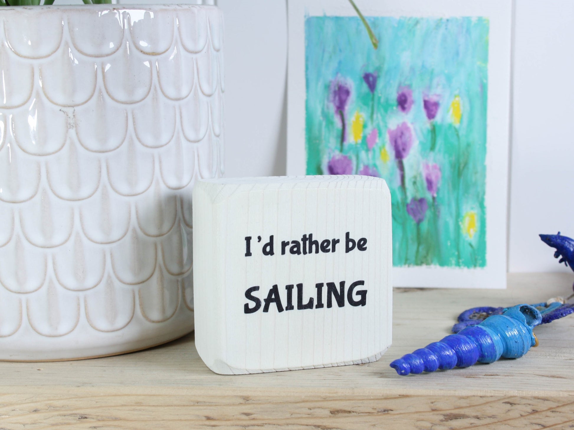 Small whitewashed wood sign with the saying "I'd rather be sailing"