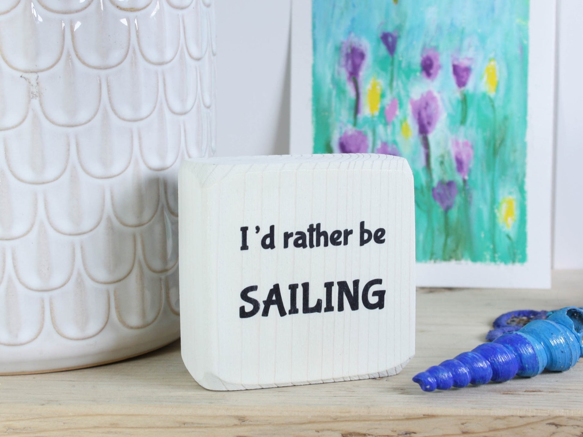 Small whitewashed wood sign with the saying "I'd rather be sailing"