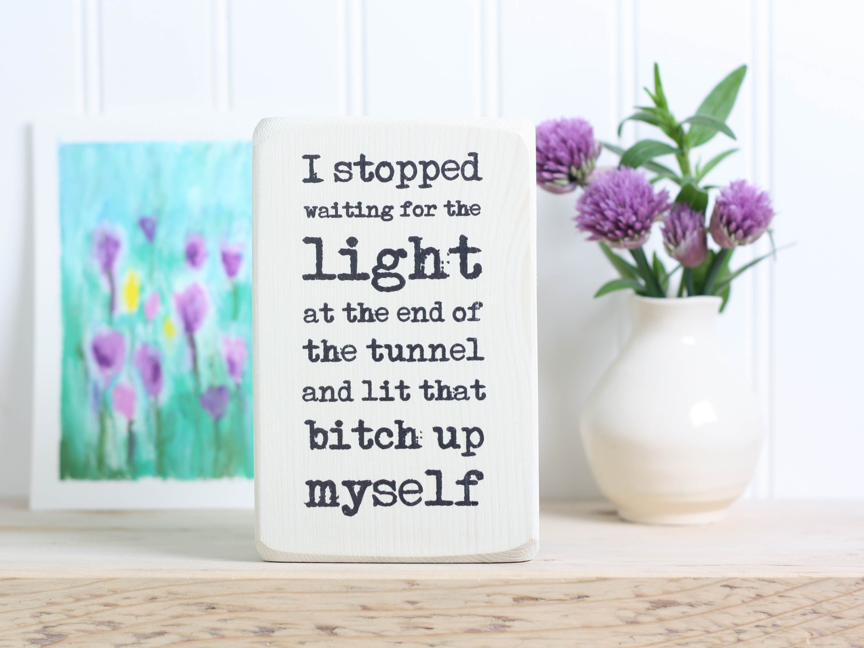 Small wood quote block in whitewash with the saying "I stopped waiting for the light at the end of the tunnel and lit that bitch up myself."