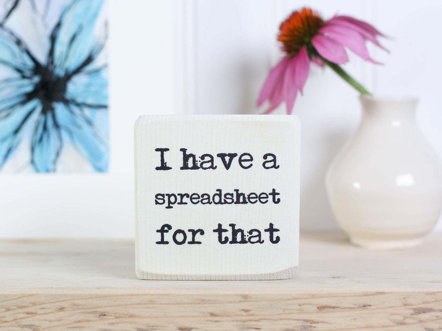 Small wood sign in whitewash with the saying "I have a spreadsheet for that."