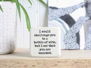 Small wood shelf decor in whitewash with the saying "I would challenge you to a battle of wits, but I see that you are unarmed."