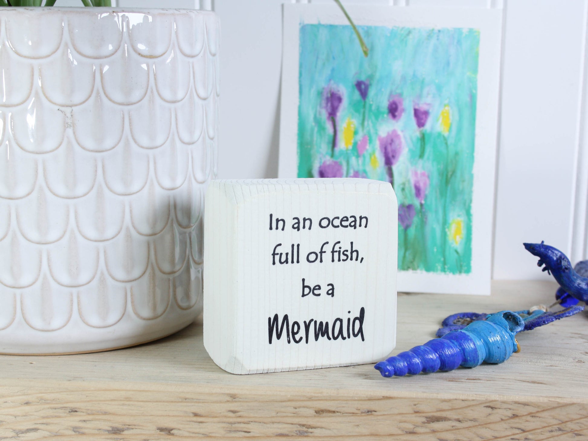 Small distressed black wood sign with the text "in an ocean full of fish, be a mermaid"
