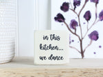 Small wooden decor in whitewash with the saying "in this kitchen... we dance"