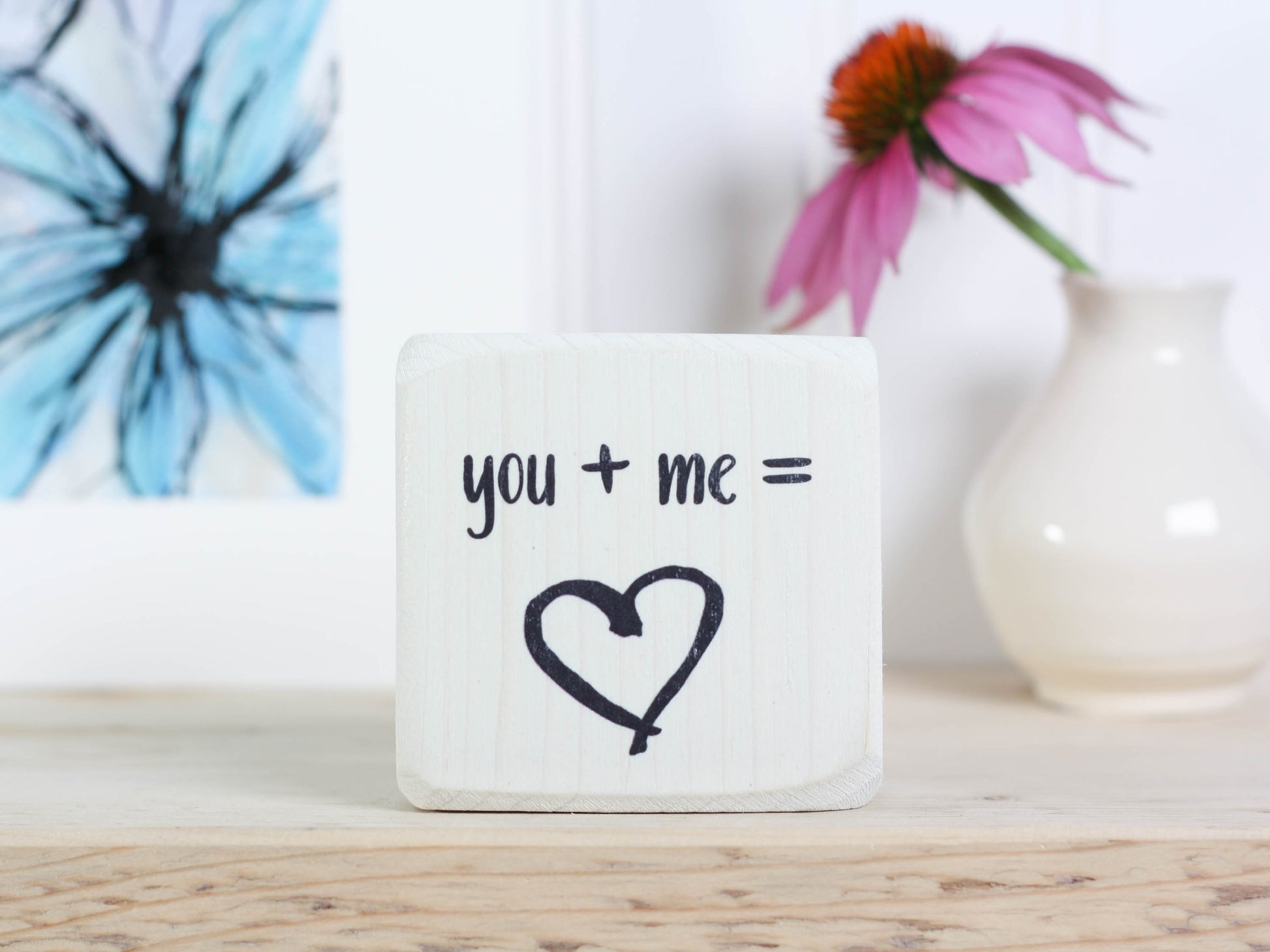 Mini wood shelf sign in whitewash with the text "you + me = (heart image)"