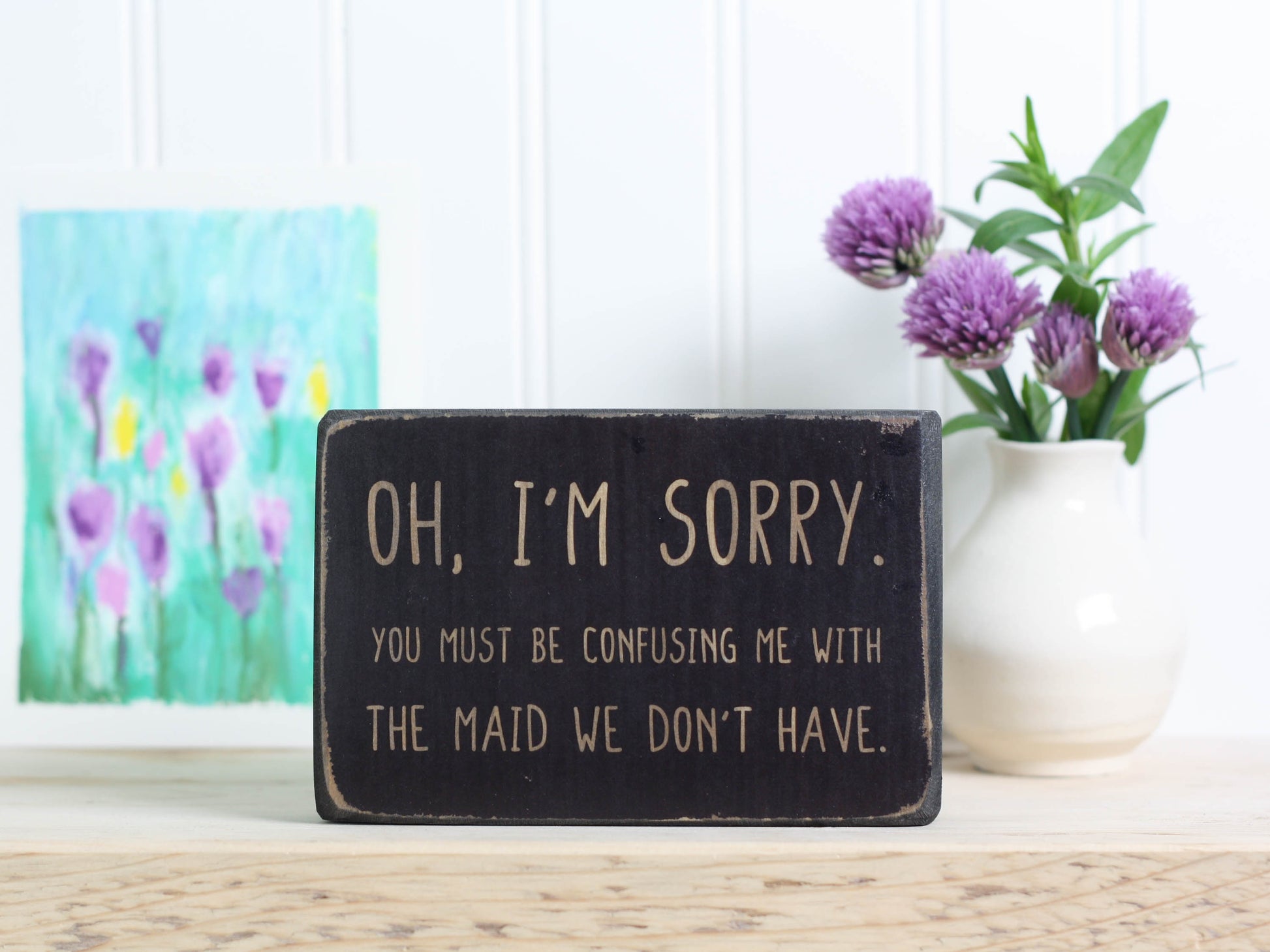 Small wood decor sign in distressed black with the saying "Oh, I'm sorry. You must be confusing me with the maid we don't have."