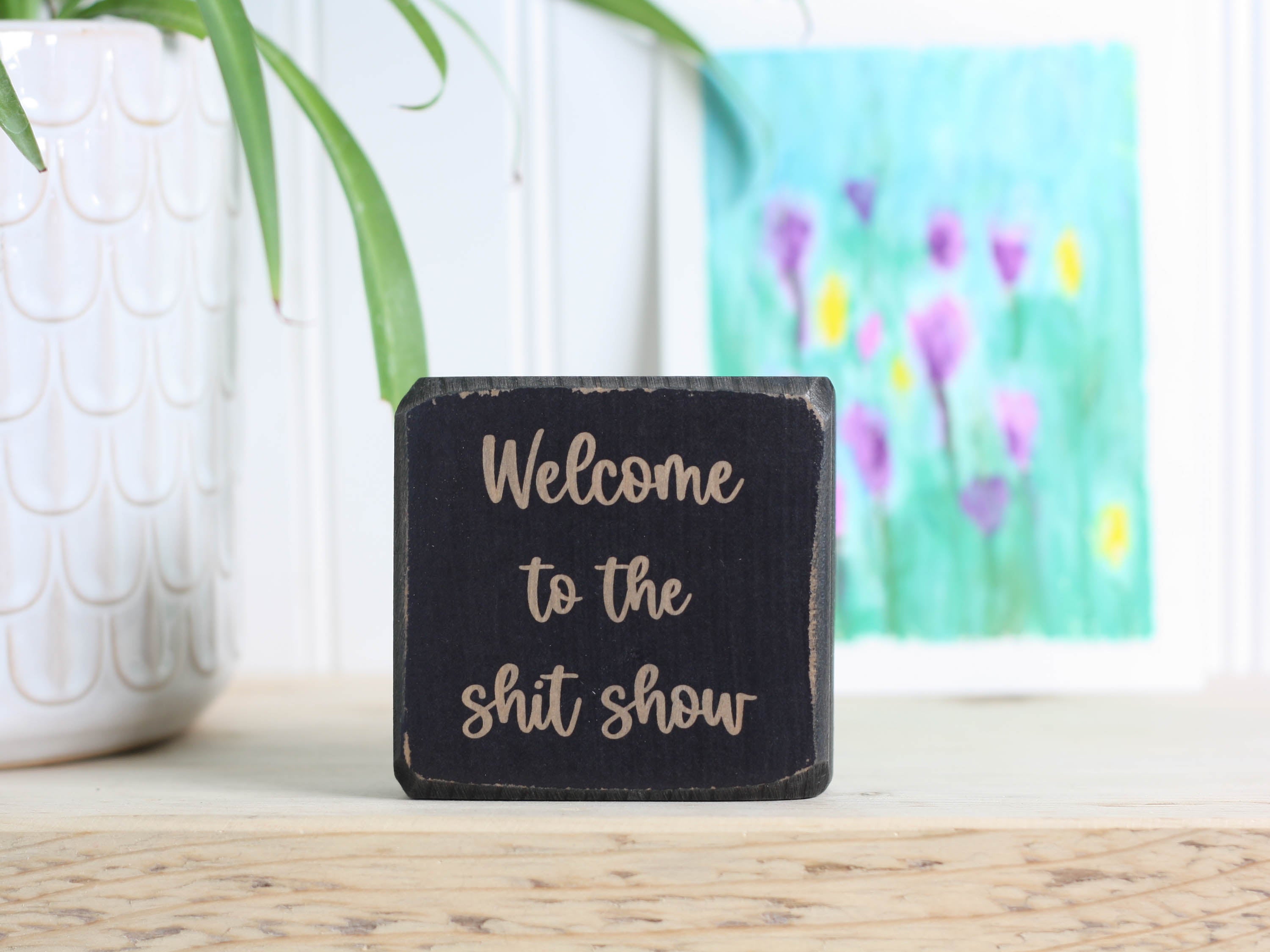 Small wood shelf sitter in distressed black with the saying "Welcome to the shit show".