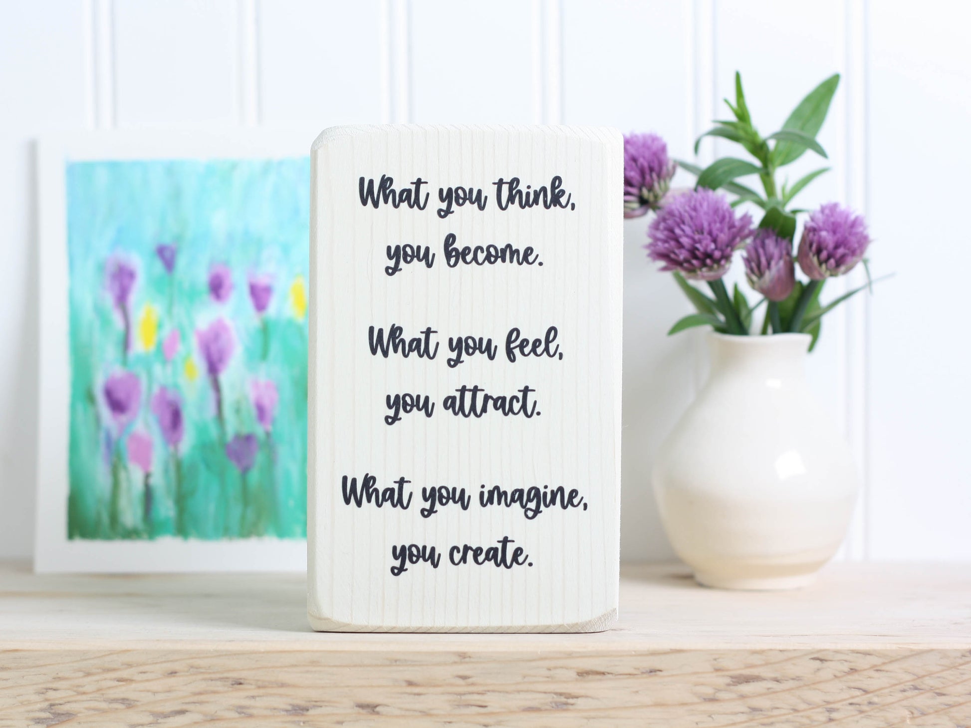 Small whitewashed wood block sign with the text "What you think, you become. What you feel, you attract. What you imagine, you create."