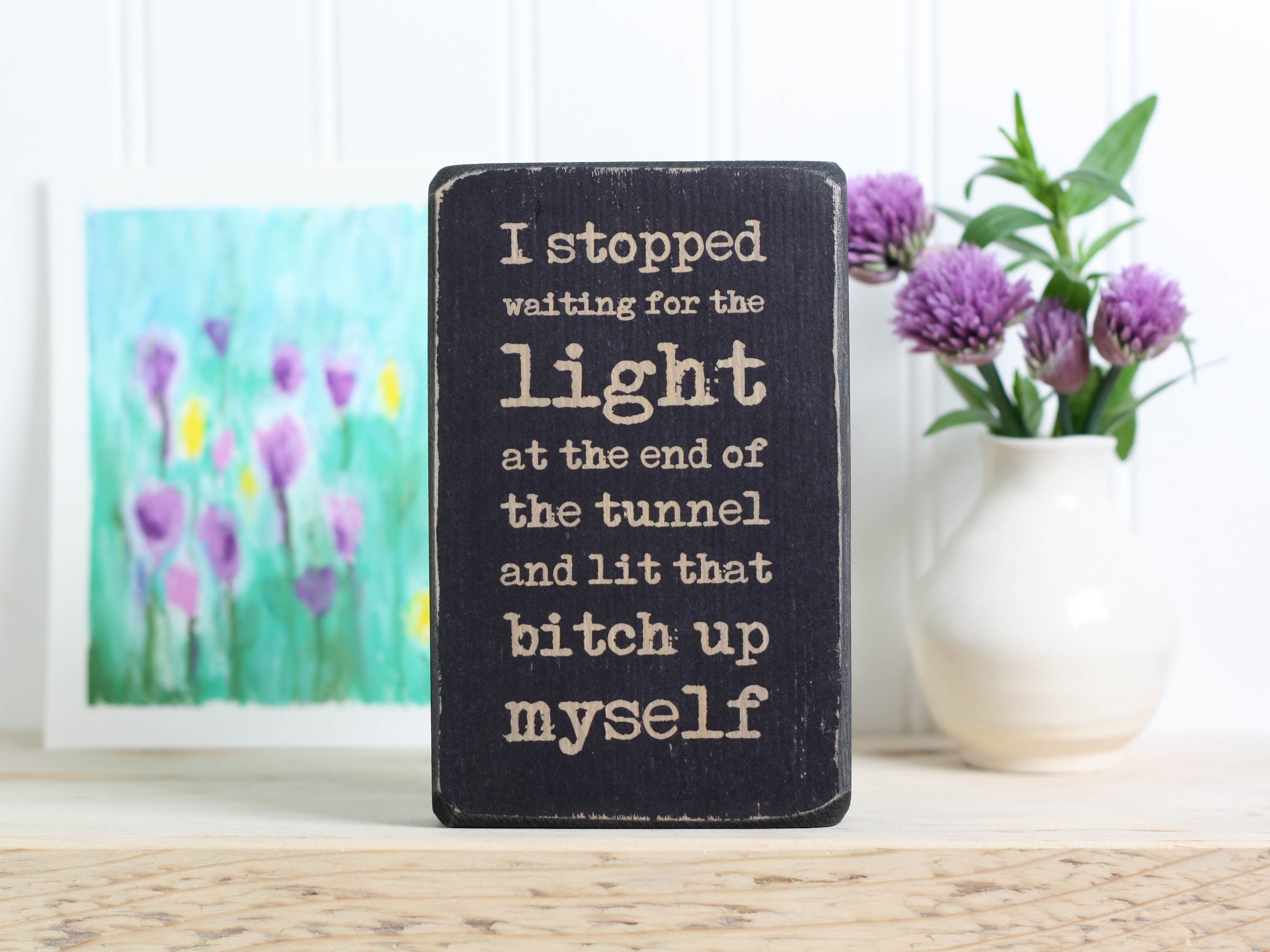 Small wood quote block in distressed black with the saying "I stopped waiting for the light at the end of the tunnel and lit that bitch up myself."
