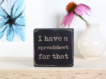 Small wood sign in distressed black with the saying "I have a spreadsheet for that."