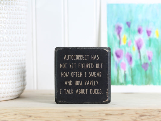 Small, freestanding, distressed black, solid wood sign with saying "autocorrect has not yet figured out how often I swear and how rarely I talk about ducks."