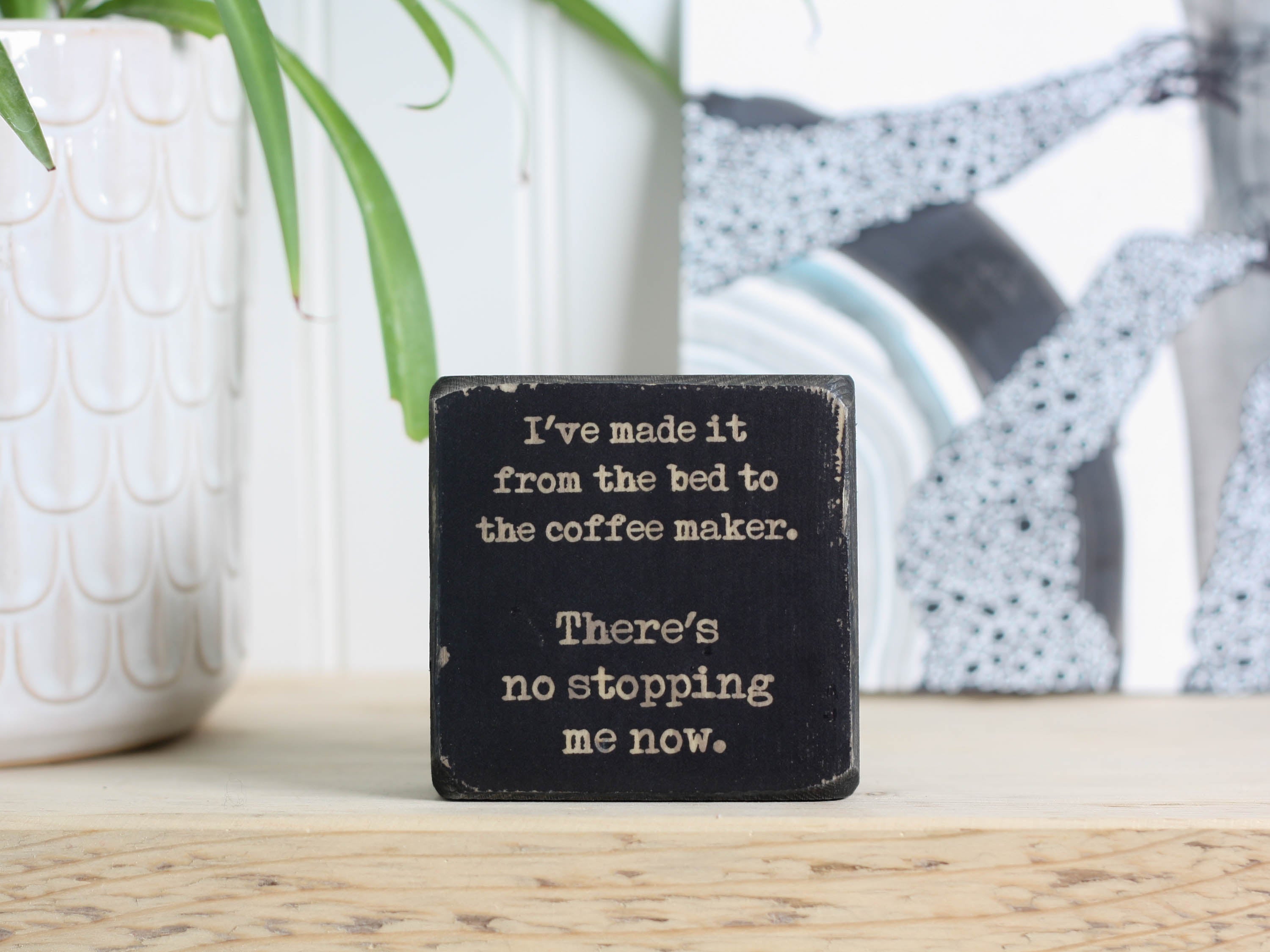 Small wood sign for kitchen in distressed black with the saying "I've made it from the bed to the coffee maker. There's no stopping me now."