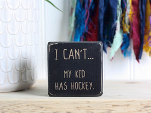 Mini distressed black wood sign with the saying "I can't... my kid has hockey."