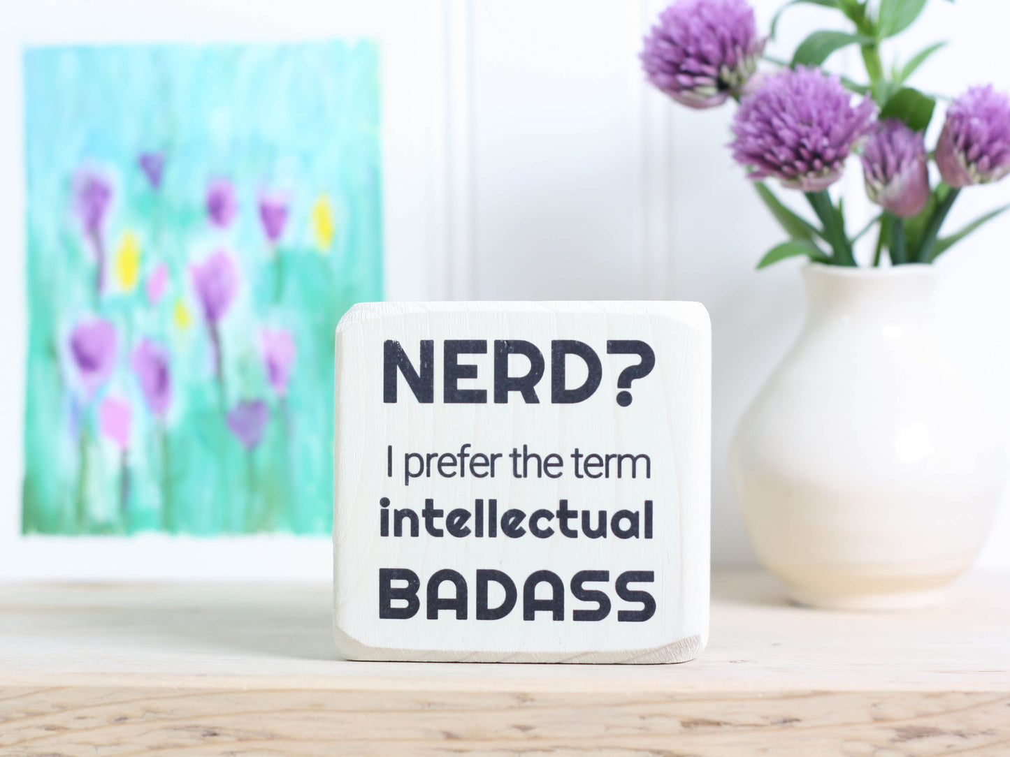 Small desk sign in whitewash with the saying "Nerd? I prefer the term intellectual badass."