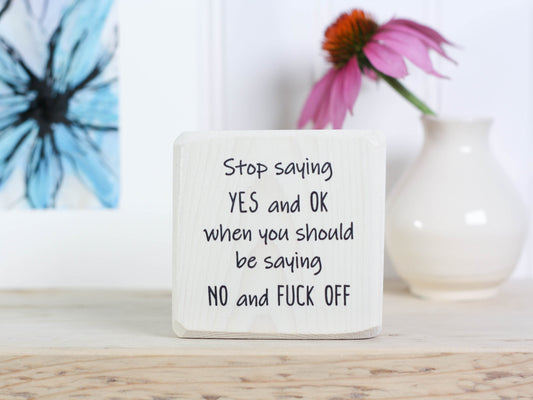 Small whitewash freestanding wood sign with the text "stop saying yes and ok when you should be saying no and fuck off"