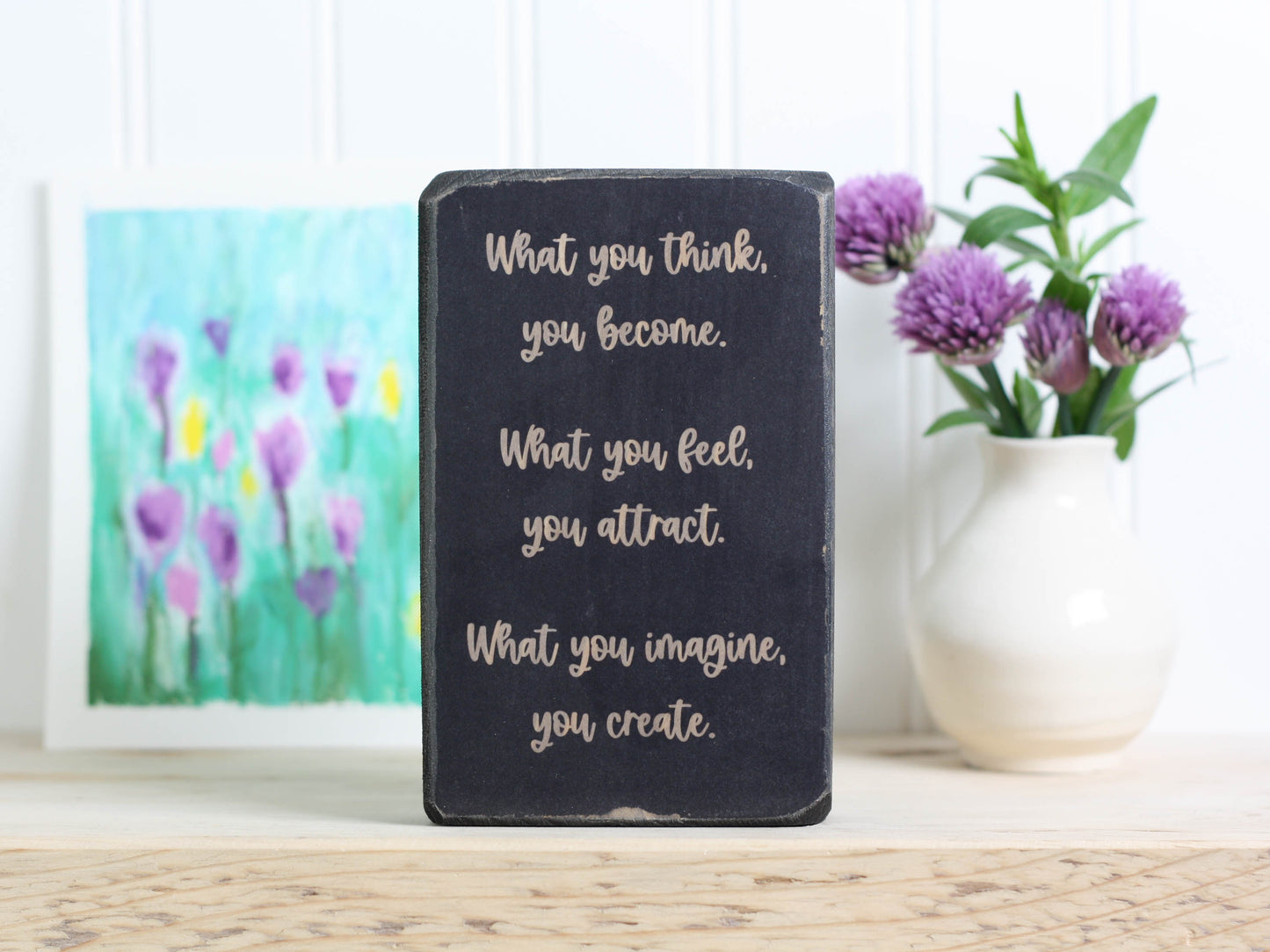 Small distressed black wood block sign with the text "What you think, you become. What you feel, you attract. What you imagine, you create."