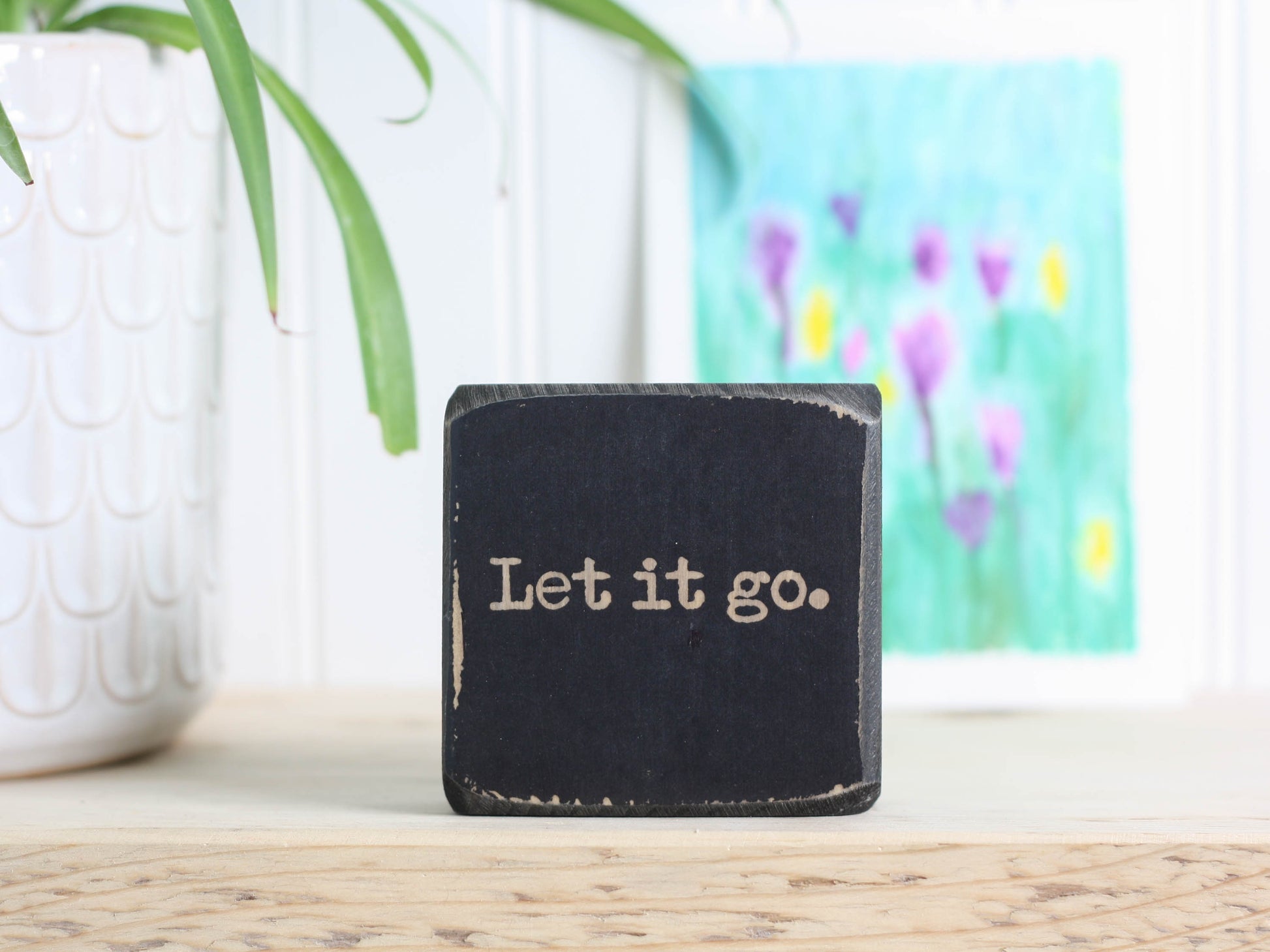 Small wood inspirational sign in distressed black with the saying "Let it go."