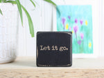 Small wood inspirational sign in distressed black with the saying "Let it go."