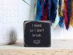 Mini wood yoga decor in distressed black with the saying "I bend so I don't break".