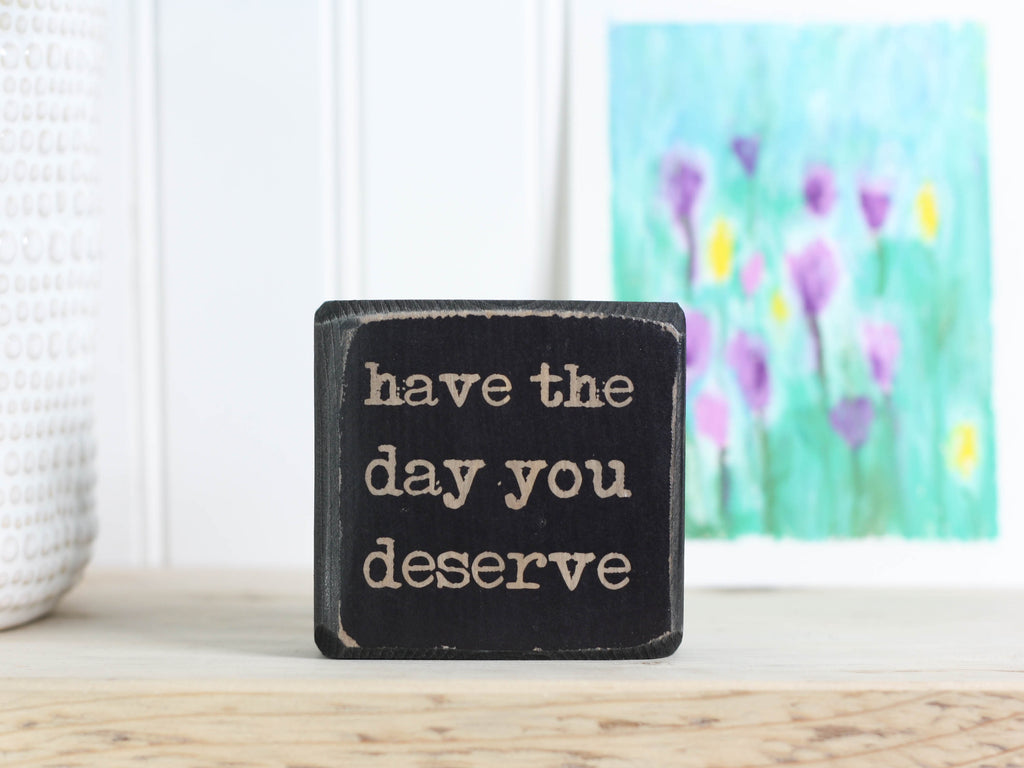 small wood sign in distressed black with the text "have the day you deserve"