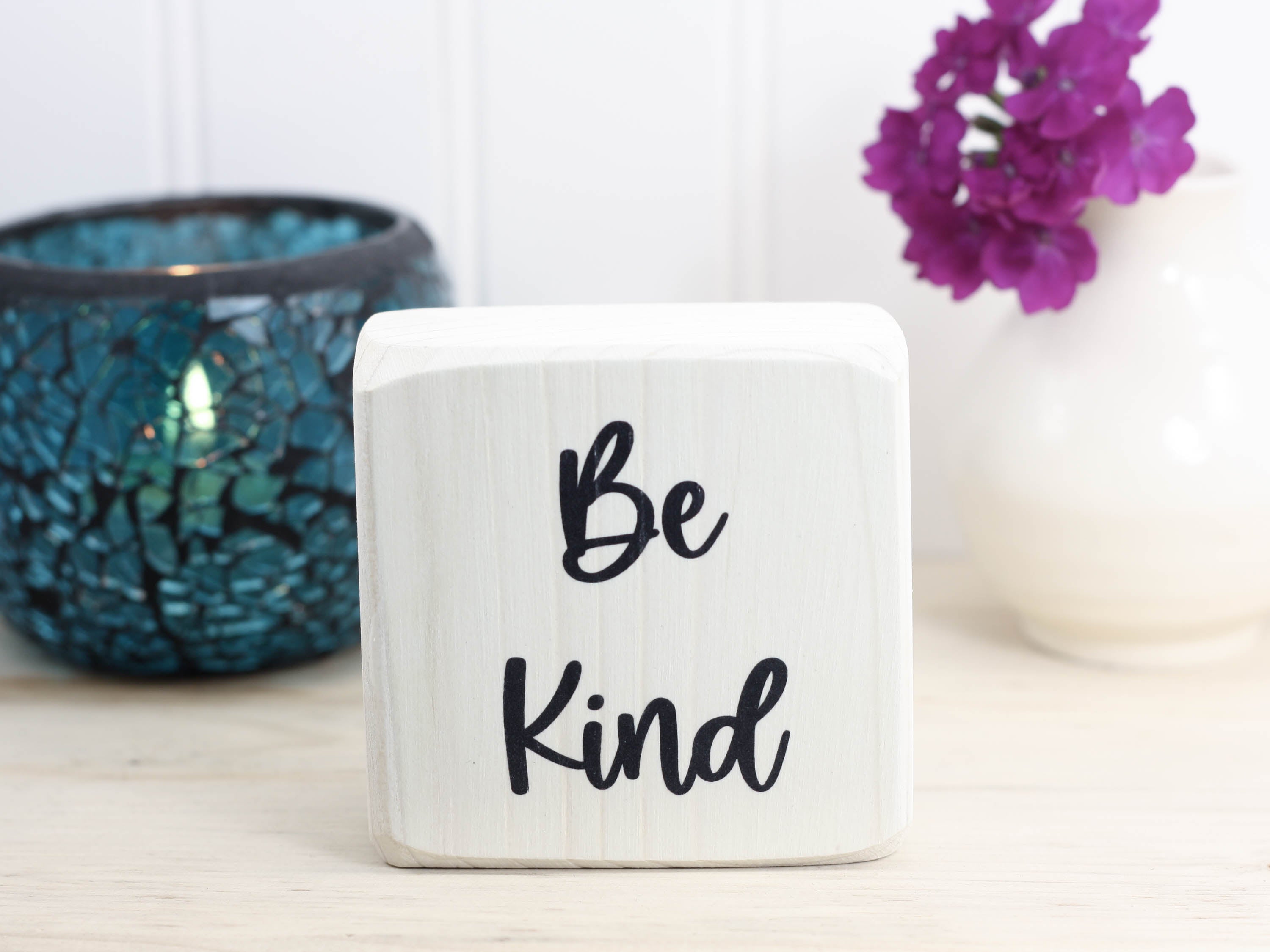 whitewashed small wood sign with the text "be kind"