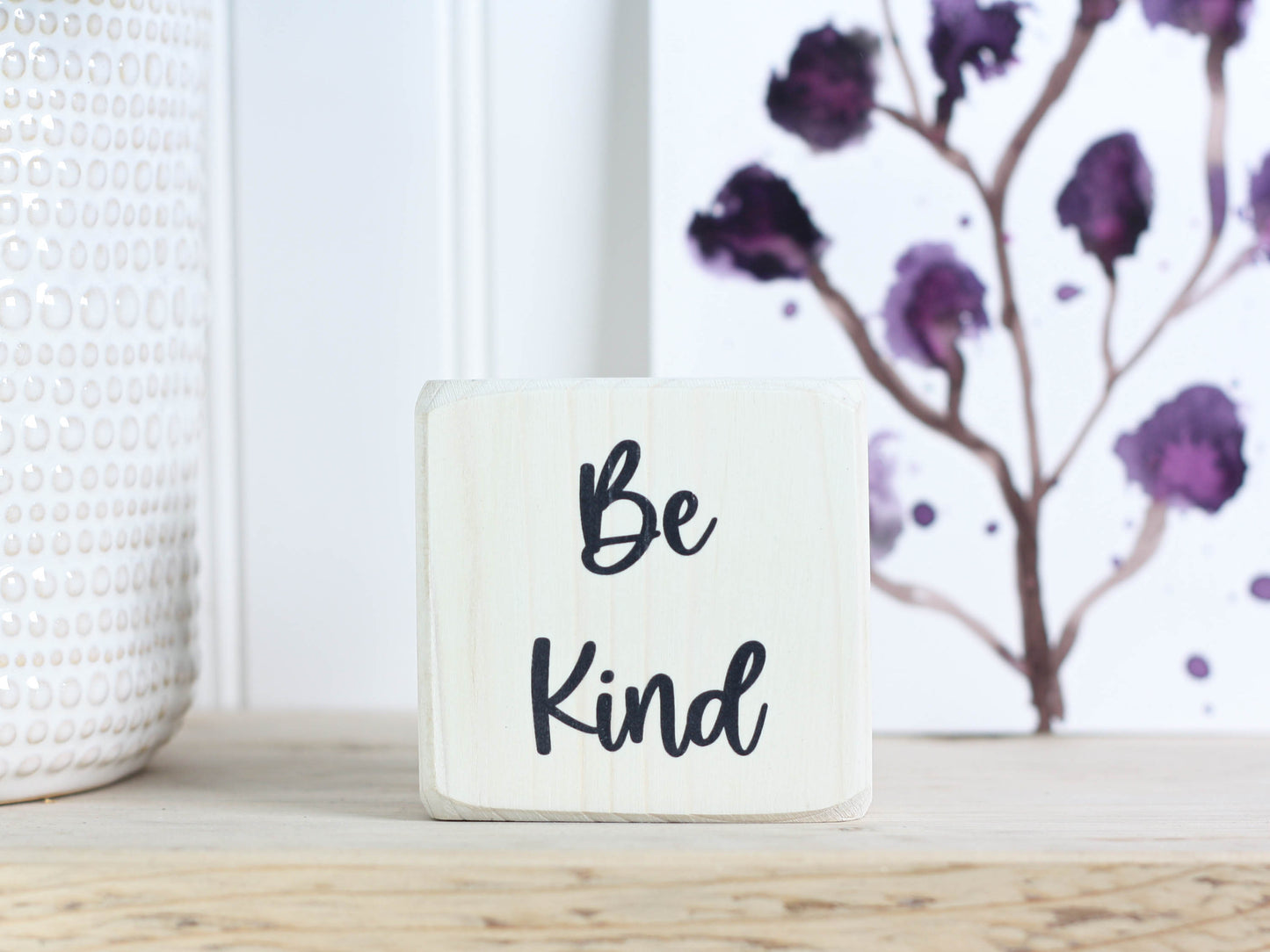 whitewashed small wood sign with the text "be kind"