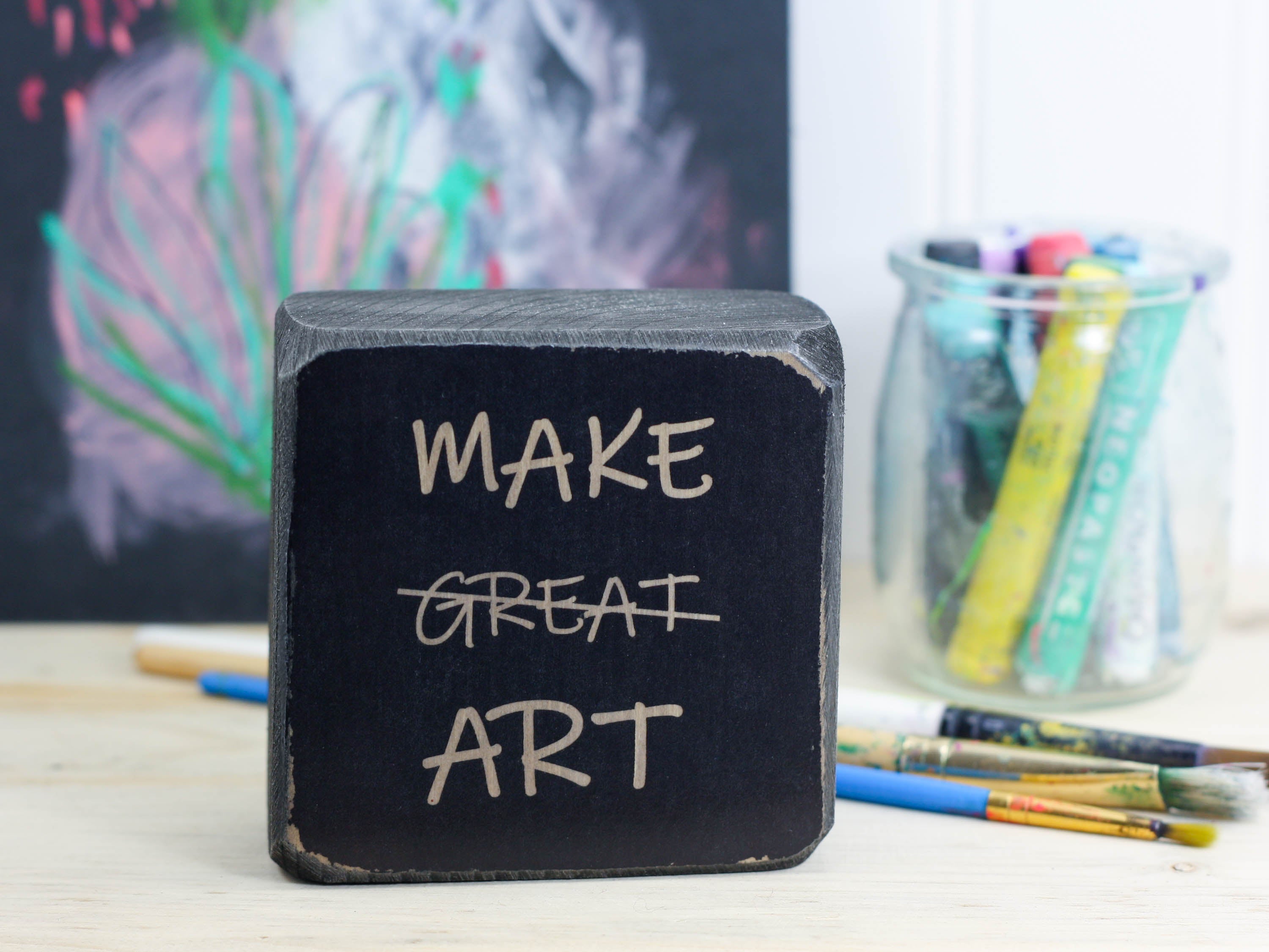 small freestanding sign in distressed black with the text "Make great art" and the word great is crossed out
