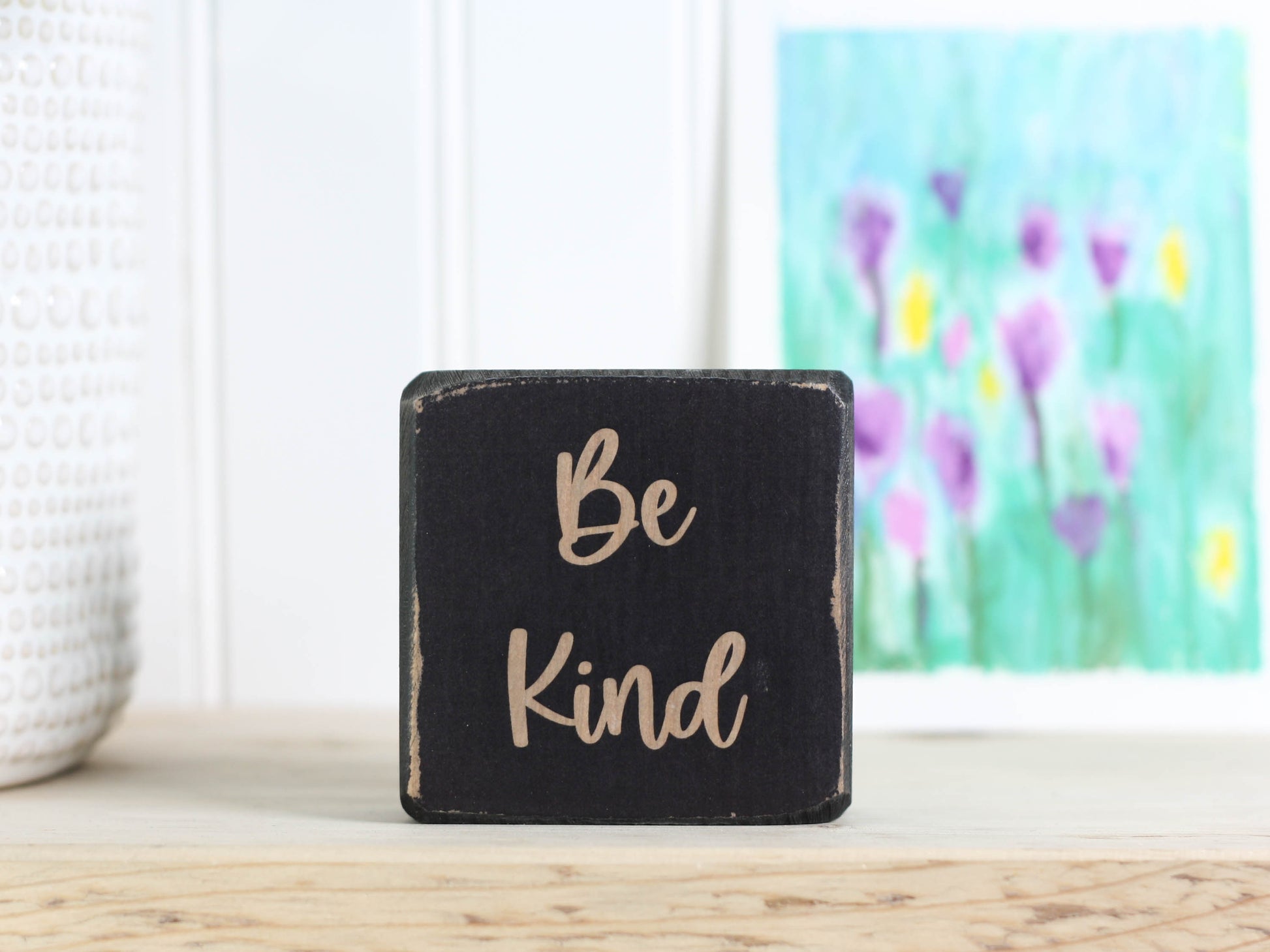 distressed black small wood sign with the text "be kind"