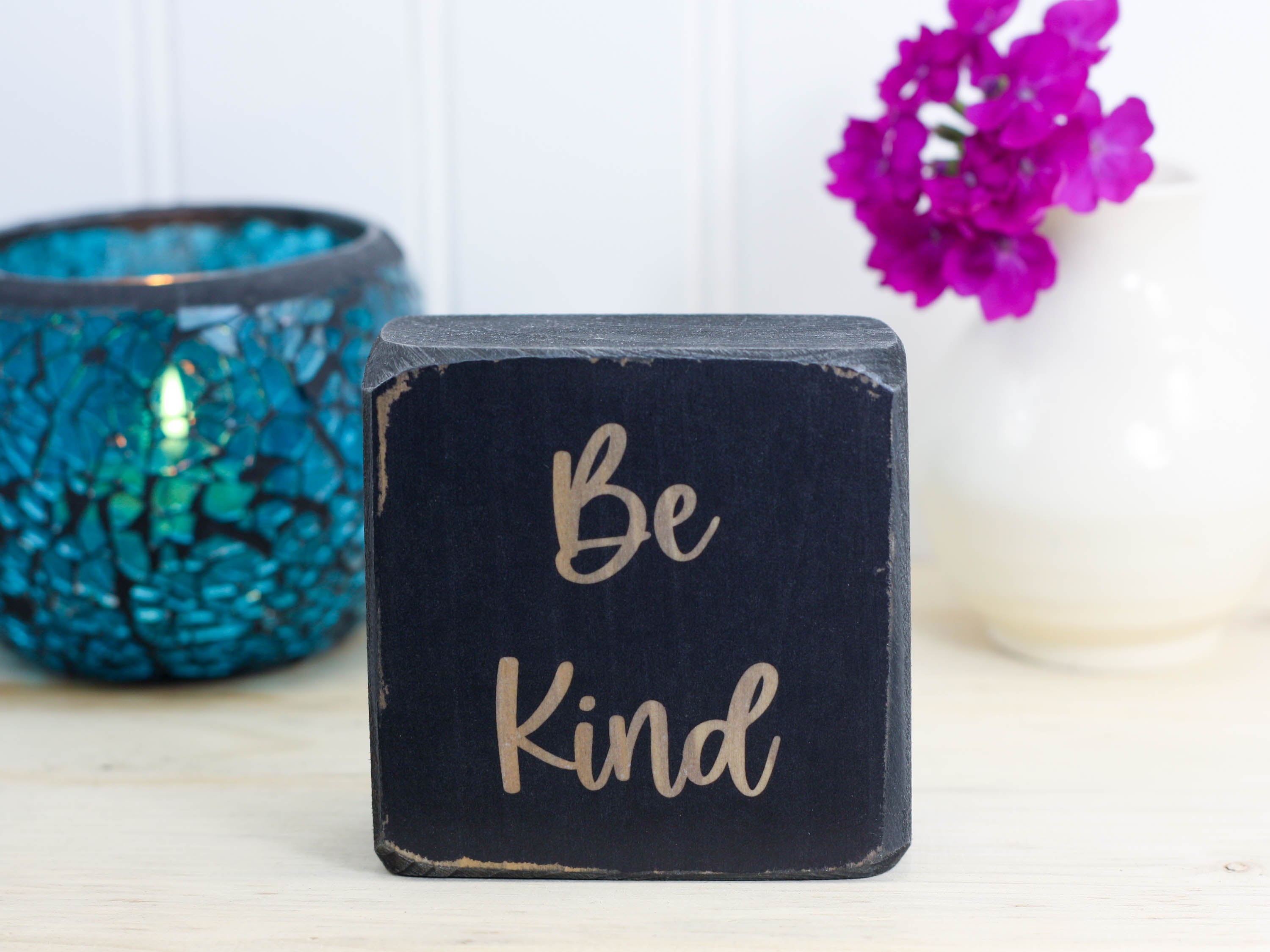 distressed black small wood sign with the text "be kind"