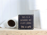 small distressed black wood bathroom sign with the text "this is a bathroom, not a wifi lounge. Shit & split"