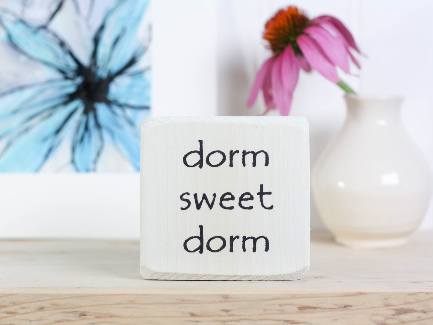 Small wood sign in whitewash with the words "dorm sweet dorm"