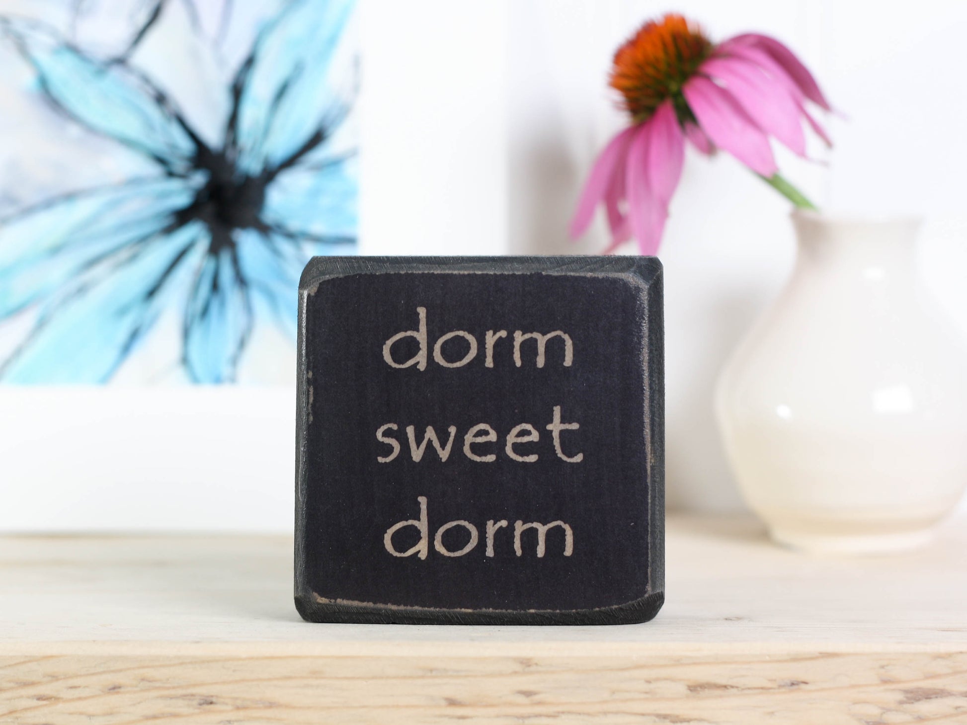 Small wood sign in distressed black with the words "dorm sweet dorm"