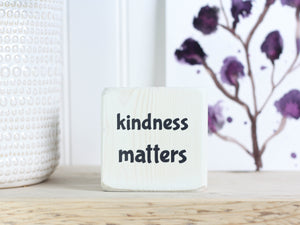 small whitewashed sign with the text "kindness matters"