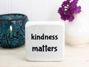 small whitewashed sign with the text "kindness matters"