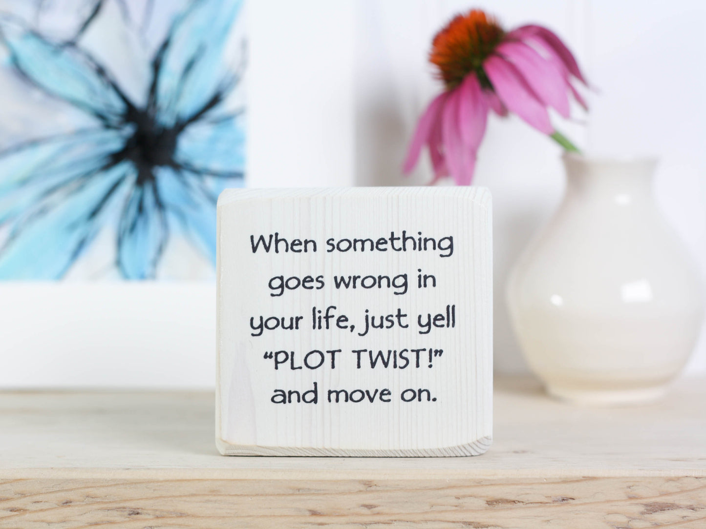 Small whitewashed wood sign with the saying "when something goes wrong in your life, just yell "PLOT TWIST" and move one. 